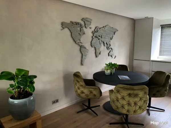 A MapaWall world map Rusty Lady from the StoneCut series installed on a concrete wall in a modern chic interior.